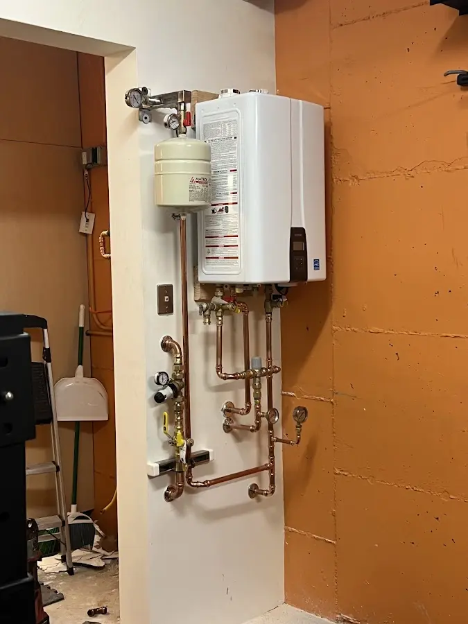 Plumbing technician inspecting water heater connections in North Valley